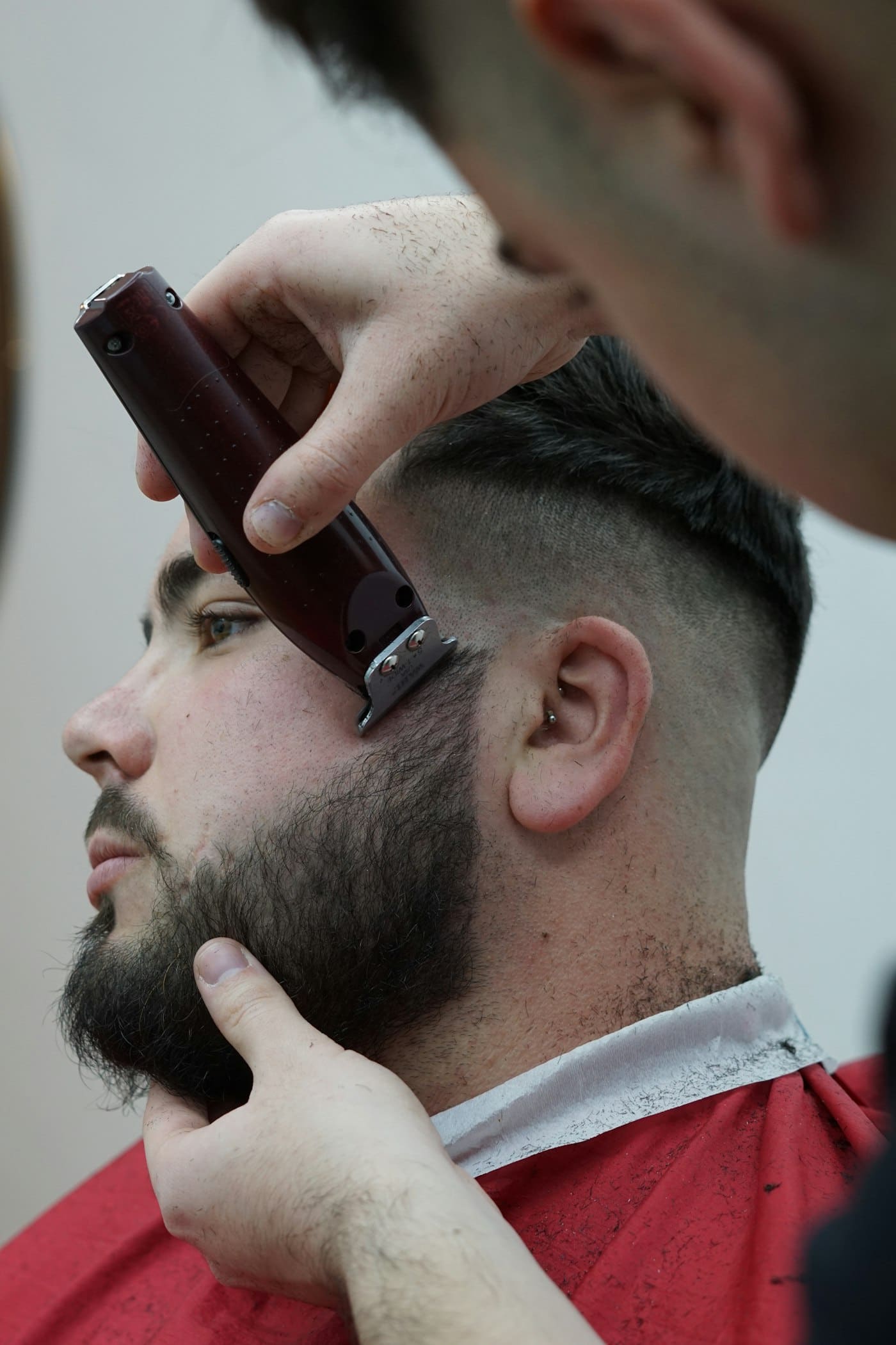 Barber lining up a beard with clippers after a skin fade