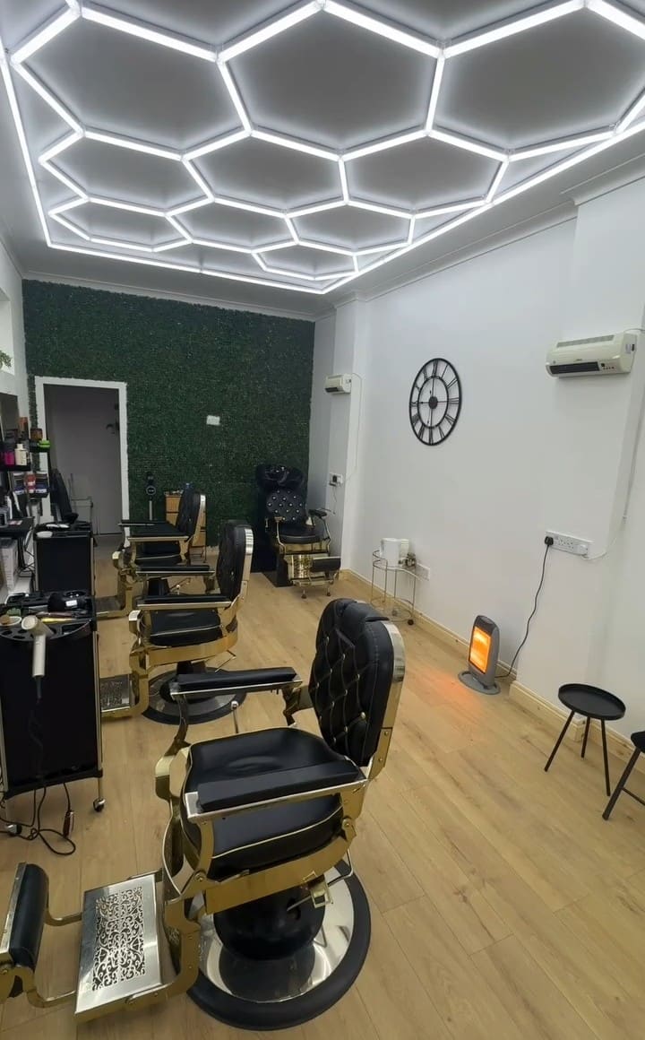 Black and gold barber chairs under the hexagon light ceiling at Zizo Barbers